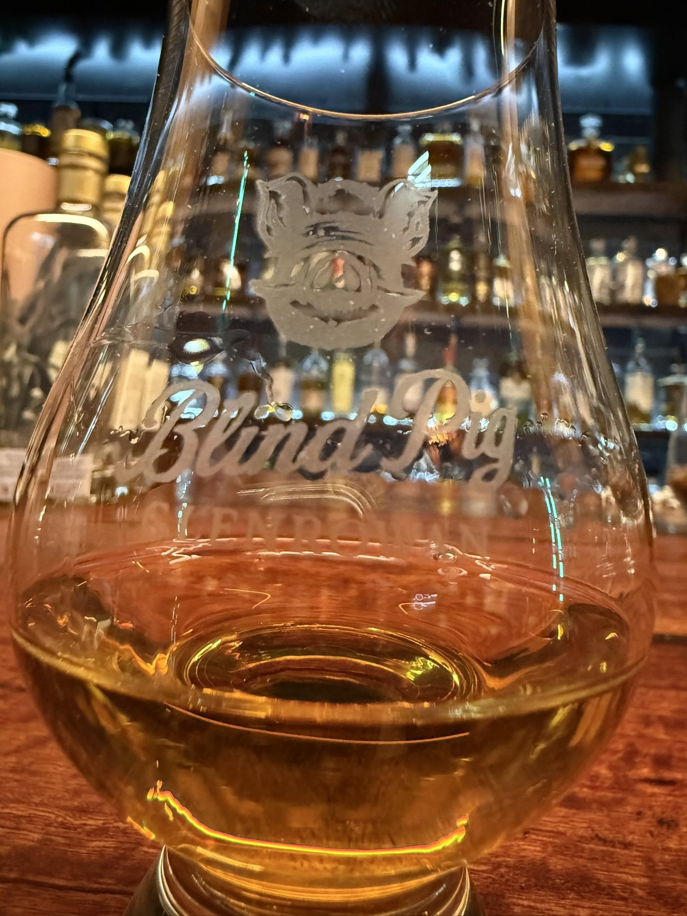 Blind Pig etched whisky glass in front of the whisky shelves